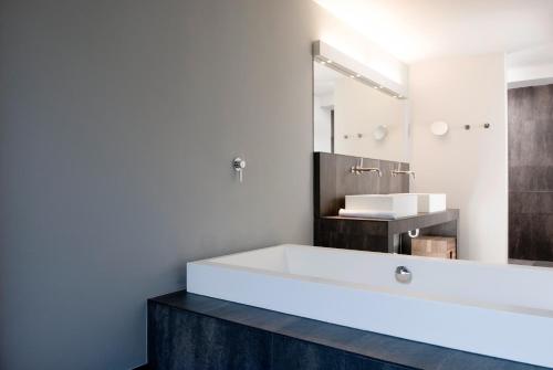 a bathroom with a large white tub and a sink at Feldmilla Design Hotel - Wellness & SPA in Campo Tures
