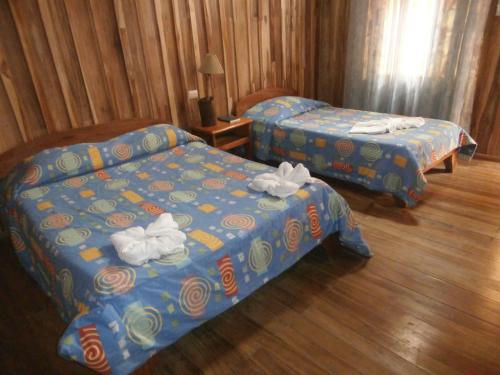 Dos camas en una habitación de hotel con toallas. en Hotel El Amanecer, en Monteverde