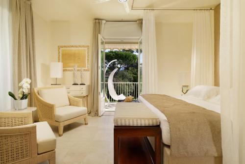a bedroom with a bed and a chair and a window at Villa Roma Imperiale in Forte dei Marmi