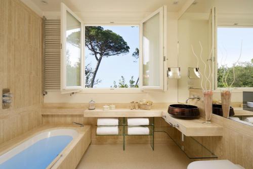 un bagno con vasca, finestra e albero di Villa Roma Imperiale a Forte dei Marmi