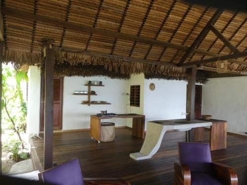 a dining room with wooden floors and a thatched roof at Picalélouba in Nosy Komba