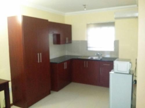 a kitchen with brown cabinets and a white refrigerator at Vido Lodge and Conference Centre in Polokwane