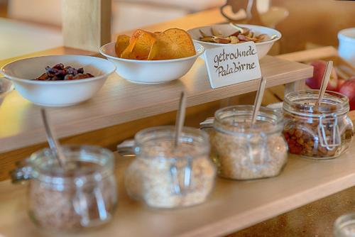 a shelf with jars of food and bowls of food at Pension Christl in Caldaro