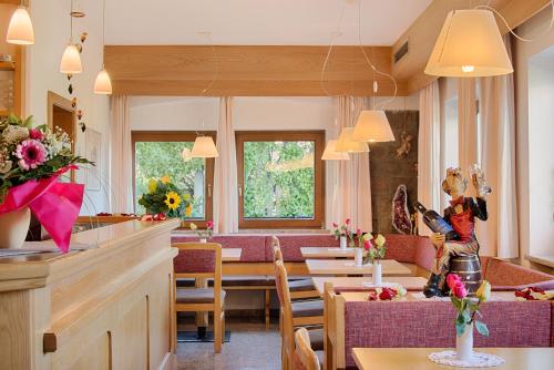 a dining room with tables and chairs and flowers at Pension Christl in Caldaro