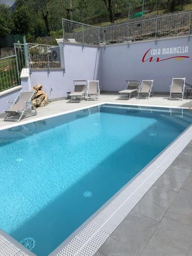 a large blue swimming pool with chairs and a wall at Hotel Casa Marinella in Malcesine