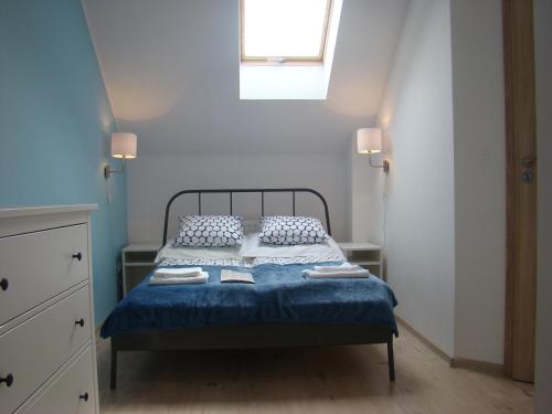 Schlafzimmer mit einem Bett mit blauer Bettwäsche und einem Fenster in der Unterkunft Słoneczny Apartament in Darłówko