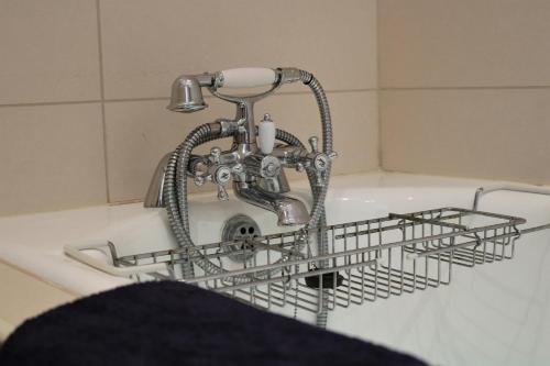 a sink with a faucet and a dish drying rack at Innishewan Farmhouse in Crianlarich