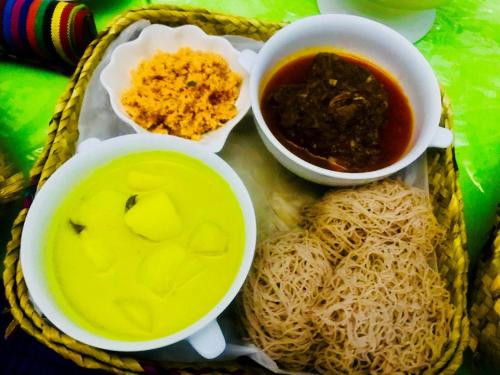 a tray of food with bowls of soup and noodles at Villa Eco Pearl in Hikkaduwa