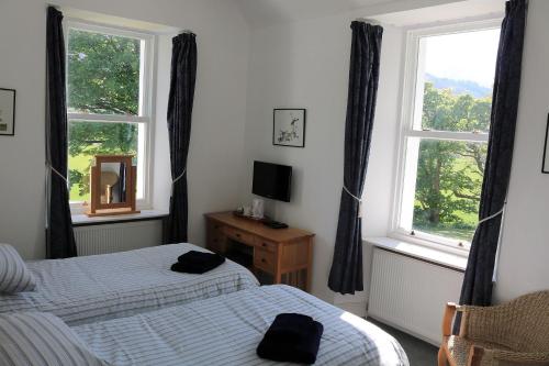 um quarto com 2 camas e uma janela em Innishewan Farmhouse em Crianlarich