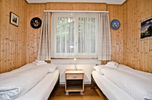 2 Betten in einem Zimmer mit Fenster in der Unterkunft Apartment Schönegg - GRIWA RENT AG in Grindelwald