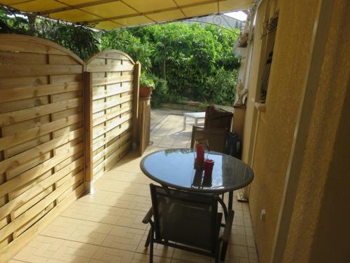 un patio avec une table et des chaises et une clôture dans l'établissement charmant appartement Saint Gély, à Cornillon