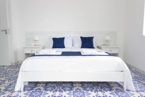 a bedroom with a large white bed with blue pillows at Angiem Holiday House Ravello in Ravello