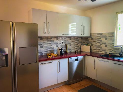 a kitchen with white cabinets and a stainless steel refrigerator at Villa Nord-Plage in Les Anses-dʼArlets