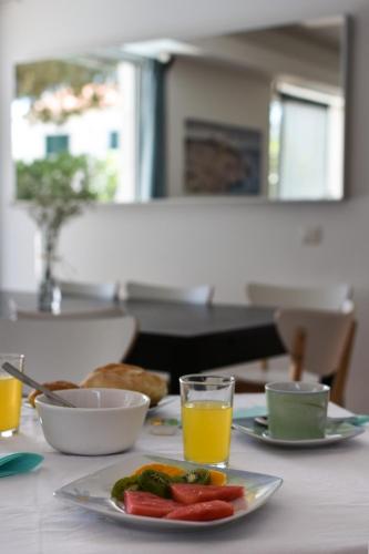 a table with a plate of food and a glass of orange juice at Pé na Areia - Guest House in Vila Real de Santo António