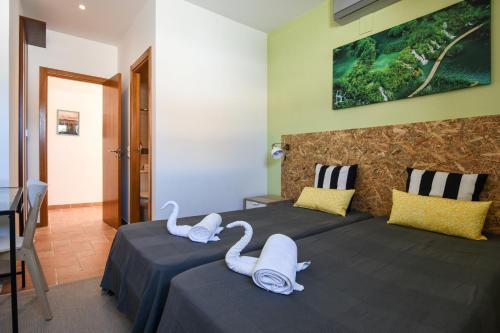 two swans sitting on two beds in a room at Pé na Areia - Guest House in Vila Real de Santo António