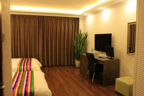 a hotel room with a bed and a desk with a computer at Hanshi Hotel Yanji in Yanji