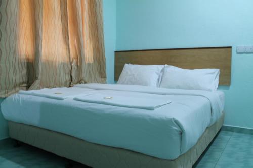 1 cama con sábanas blancas y almohadas en una habitación en Rose Inn Motel en Kuah