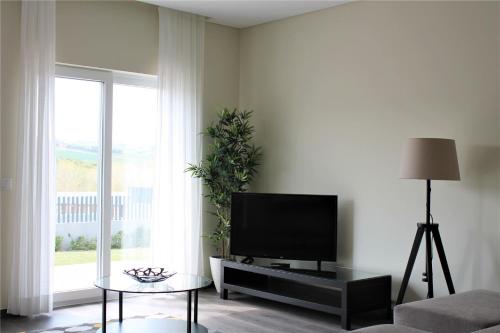 a living room with a flat screen tv and a table at Vale de Lourinhã - Casas de Campo in Lourinhã