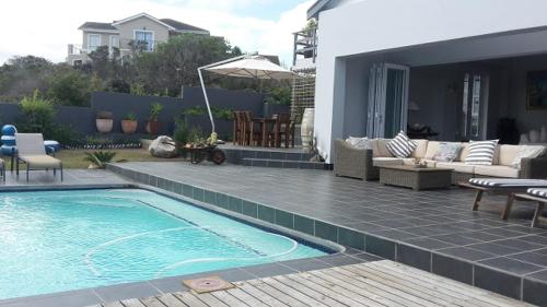 a backyard with a swimming pool and a patio at Pezula Golf House in Knysna