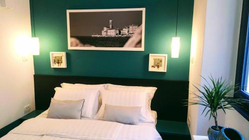 een groene slaapkamer met een bed met witte kussens bij Casa Al Porto Antico in Piran