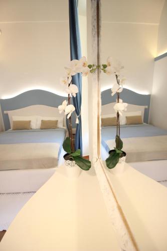 two white flowers in vases on a wall in a bedroom at S'O Smart B&B Tropea in Tropea