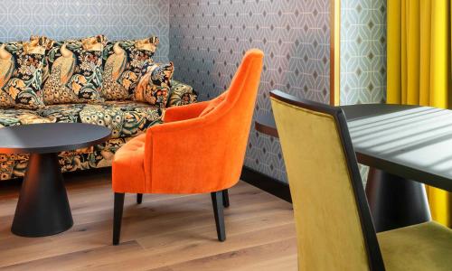 an orange chair sitting next to a table and a couch at Thon Hotel Cecil in Oslo