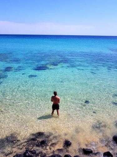a man standing in the water on a beach at Your Ocean Suite in Costa Calma