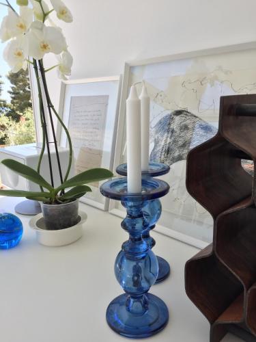 a blue candle holder with two candles on a table with flowers at Villa Mirano in Èze