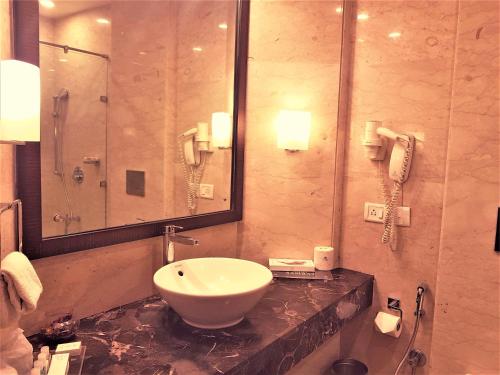 baño con lavabo, espejo y teléfono en Hotel Samrat, New Delhi, en Nueva Delhi