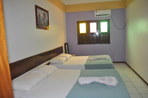 a hotel room with two beds and a window at Hotel Pousada Paraíso das Águas in Barreirinhas