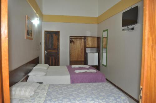 a hotel room with two beds and a television at Hotel Pousada Paraíso das Águas in Barreirinhas