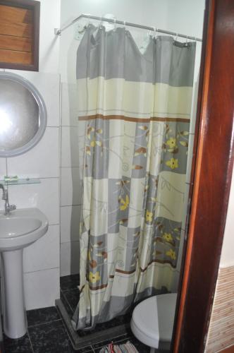 a bathroom with a shower curtain with a toilet and a sink at Hotel Pousada Paraíso das Águas in Barreirinhas