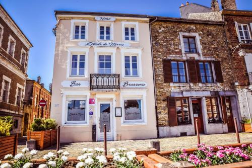 a white building on a street with flowers in front at Hôtel La Poterne du Roy in Rocroi