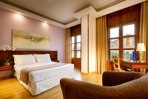 a hotel room with a bed and two chairs at Exe Triunfo Granada in Granada
