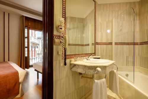 a bathroom with a sink and a bath tub at Exe Triunfo Granada in Granada