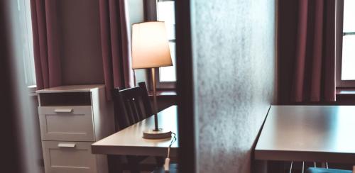 a room with a desk with a lamp and a table at Hôtel La Poterne du Roy in Rocroi