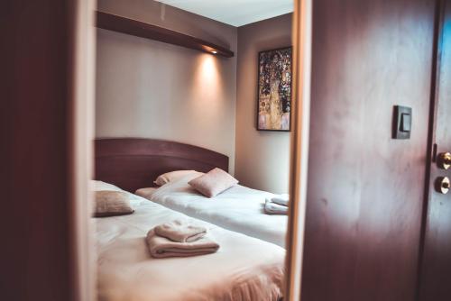 a mirror reflection of two beds in a bedroom at Hôtel La Poterne du Roy in Rocroi