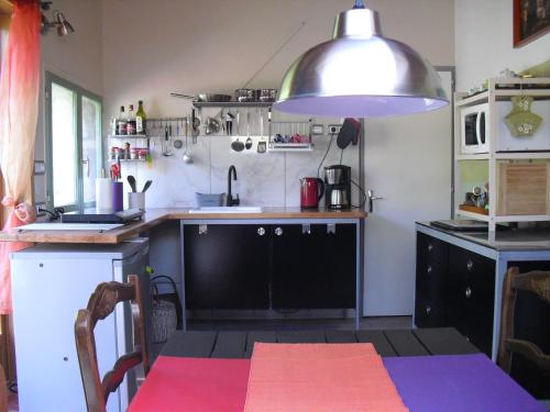 a kitchen with a table and a large pendant light at La Maison Imparfaite in Fourbanne