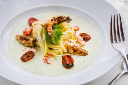 a white plate with shrimp and pasta with a fork at Tertianum Residenza Al Parco Appartements & Restaurant in Locarno