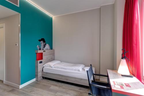 a small bedroom with a bed and a red curtain at MEININGER Roma Termini in Rome