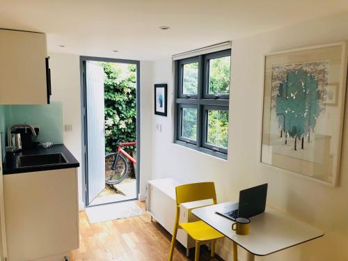 a kitchen with a desk and a laptop on a table at Camden Town Garden Cabin in London