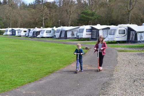 a woman and a child riding scooters on a path at Callander Woods Holiday Park in Callander
