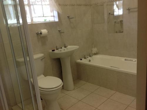 a bathroom with a toilet and a sink and a tub at Lynns Guest House in Bulawayo