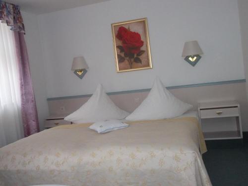 a bedroom with a white bed with a flower on the wall at Hotel am Seetor in Angermünde
