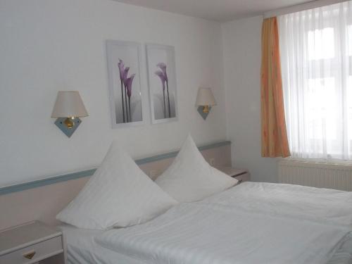 a bedroom with a white bed with flowers on the wall at Hotel am Seetor in Angermünde