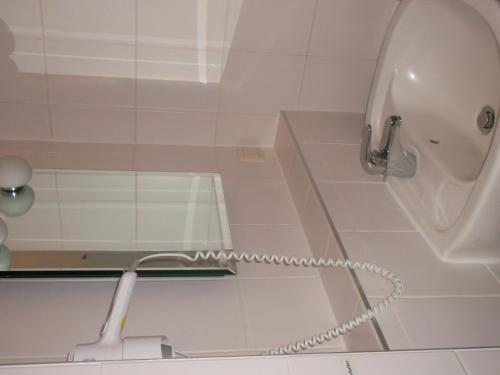a white shower with a hose in a bathroom at Hotel am Seetor in Angermünde