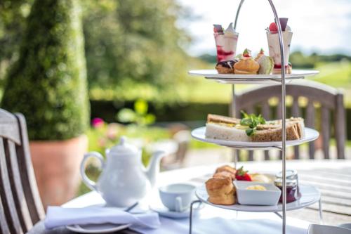a table with three tiered plates of pastries and desserts at Barnham Broom Hotel, Golf & Spa in Norwich