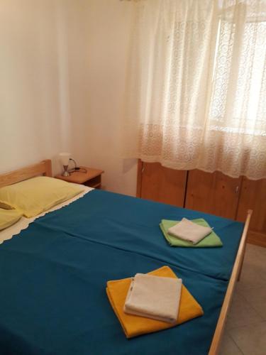 Una cama azul con dos toallas encima. en Apartman Pavao Fadić, en Komiža