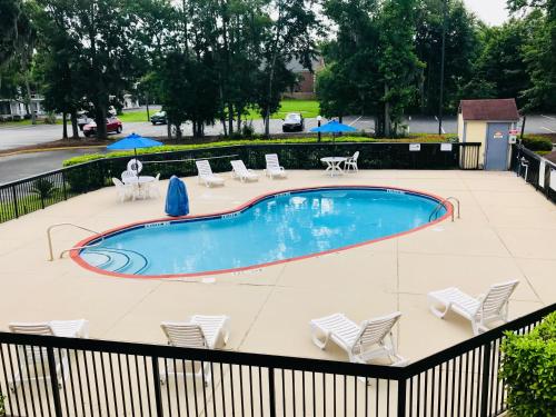 a swimming pool with chairs and tables and umbrellas at Motel 6-Savannah, GA - Midtown in Savannah