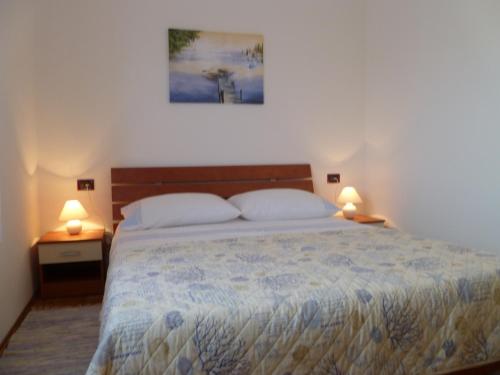 - une chambre avec un grand lit et 2 lampes sur les tables dans l'établissement Appartamento Camelia, à Fažana